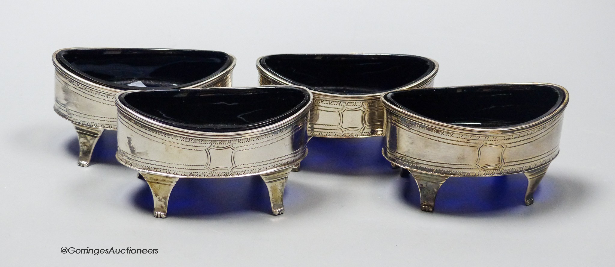 A set of four George III silver oval boat shaped salts, with blue glass liners, Robert Jones II, London, 1796, 88mm.